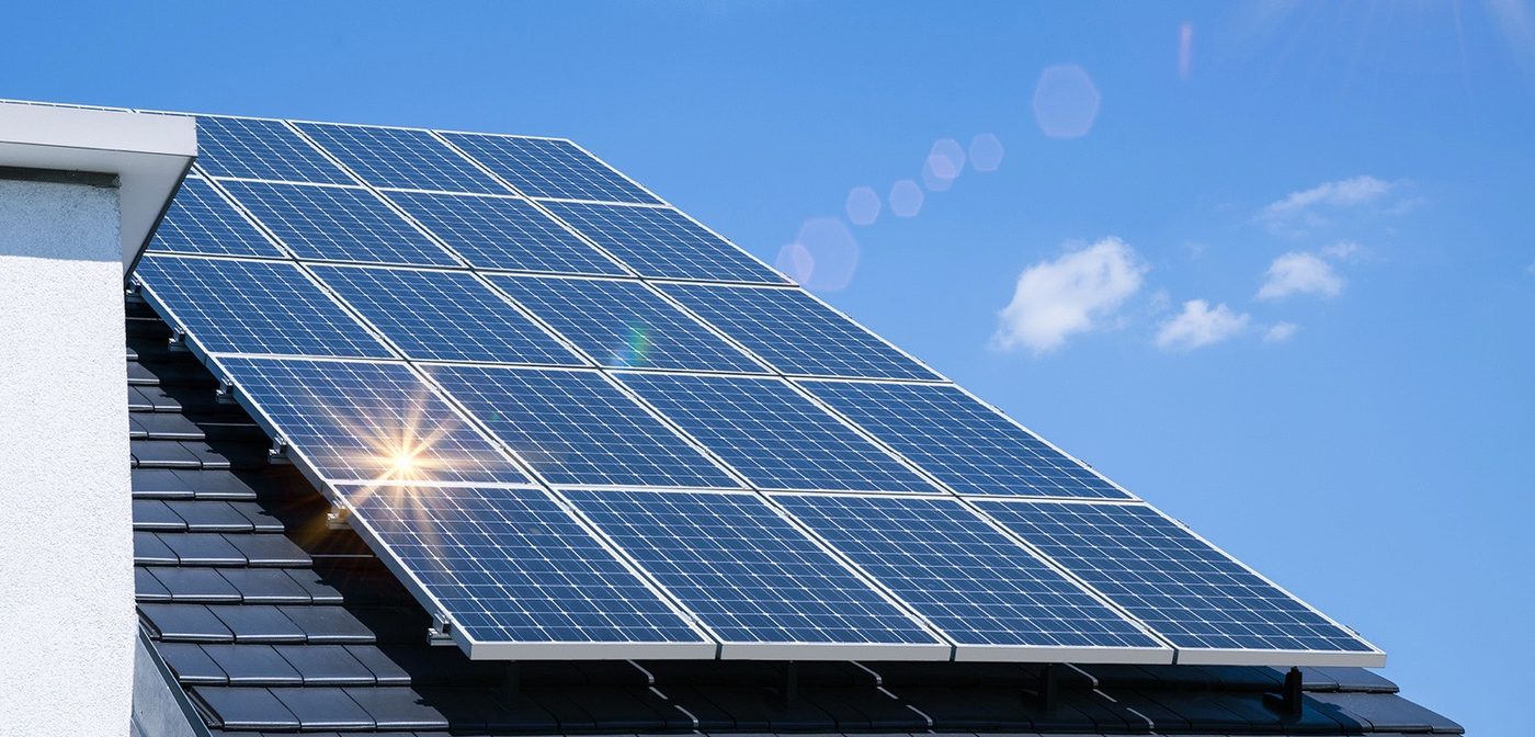 Photovoltaik-Anlage auf einem Satteldach vor blauem Himmel